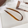 Macro detail of amber tortoiseshell U-shaped hair pin on elegant textured glass surface - Brown