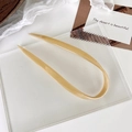 Detailansicht der glatten U-förmigen Haarnadel in Beigecrème auf einem Glastablett - Milchtee-Farbe