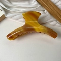 Détail d'une grande pince à cheveux en acétate ambre marbré sur cuir blanc élégant - Grand / Ambre