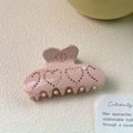 Vue détaillée d'une pince à cheveux rose en forme de cœur avec strass et logo CD - Grande Pince à Cheveux / Rose