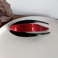 Detail showing the red and black glossy resin hair claw clip with a sleek leaf design - Red