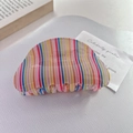 Detail of colorful rainbow striped acetate claw clip on a minimalist white texture background - Vertical Rainbow Stripe Style