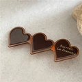 Dettaglio di un fermaglio a cuore in tartaruga con scritta dorata su fondo di pietra - Cuore Caffè Scuro