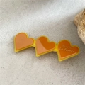 Dettaglio macro di tre fermagli a cuore in resina ambra con scritta Barrette La France - Cuore Arancione