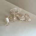 Gros plan sur la pince à cheveux ondulée transparente avec détails en feuille d'or - Champagne
