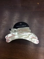Close-up of a white marble texture rabbit hair claw clip on a dark wood surface - White Rabbit