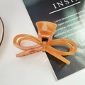 Detail of an amber acetate bow hair claw clip with marble texture on a fashion magazine - Caramel color