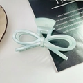 Detailed view of mint green acetate bow hair claw clip on a stylish fashion magazine - Blue