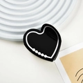 Dettaglio di molletta per capelli a cuore in acetato nero con perle su sfondo decorativo - Nero