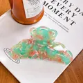 Makroaufnahme der großen Retro-Haarklammer aus Acetat mit Marmormuster auf einem Magazin - Floral Grün