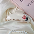 Detail of a creamy white acetate hair claw with red floral patterns and tiny rhinestones - One Flower Style (9cm)