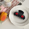 Detail of black hair claw clip with red apple decoration and rhinestones on white plate - 8cm x 4.5cm / Black Apple