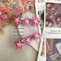 Gros plan de barrettes étoiles roses pailletées sur un fond de magazine esthétique - Rose Bonbon