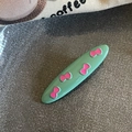 Close-up of a mint green oval hair clip decorated with pink bow patterns - Grass Green