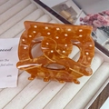 Close-up of amber acetate hair claw clip with white polka dots on a jewelry tray - Large (8cm) / Caramel color
