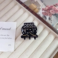 Detail of black acetate hair claw with white polka dots and gold wave lines on cream tray - Small (3.5cm) / Black