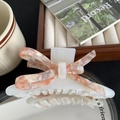 Detailweergave van een elegante haarklem in de vorm van een strik met marmeren textuur - Parelwit
