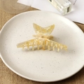 Détail d'une pince à cheveux papillon avec lettre B dorée sur surface crème marbrée - Light jaune