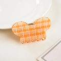Vista dettagliata di un fermaglio per capelli a farfalla con motivo pied de poule arancio - Arancione / 7.5cm