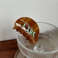 Detailaufnahme der bernsteinfarbenen Haarklammer aus Acetat mit blauem LIKE-Schriftzug - 8.5cm / Kaffeebraun