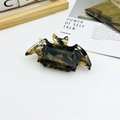 Detail of bat-shaped hair claw clip with yellow and black tortoiseshell texture pattern - Caramel color