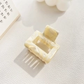 Detail view of a cream marble acetate hair claw clip on a textured white surface - Small / Off-white
