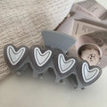 Dettaglio della pinza per capelli grigia in acetato con 4 cuori su tessuto beige - 9.6cm / Grigio
