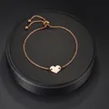 Vue détaillée du bracelet cœur en or rose réglable avec fermoir coulissant sur un support noir - Or rose