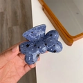 Détail de la pince à cheveux papillon en denim bleu avec motifs étoiles noires et ressort - 7.8cm x 5.5cm / Bleu Denim Étoile Noire