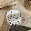 Detailweergave van een witte volleybal haarklem met zwarte lijnpatronen op de clip - Witte Volleybal