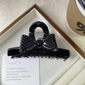 Close-up of a glossy black hair claw clip featuring a polka dot bow tie on a wooden tray - Glossy Pure Black