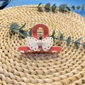 Détail d'une pince à cheveux rose avec nœud en dentelle blanche sur un tapis de paille - Pince à cheveux / Rose & Blanc