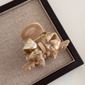 Detail showing marble-patterned acetate bow hair claw clip with sturdy metal spring mechanism - 7.5cm / Light Coffee