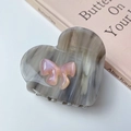 Detail of heart-shaped hair claw with marble texture and pink pearlescent bow - Gray