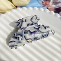 Dettaglio di un grande fermaglio per capelli marmorizzato bianco e viola su vassoio - Blu Olografico 8.5cm