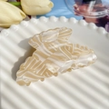 Detailed macro view of acetate hair claw clip with marble texture on decorative tray - Off-white 8.5cm