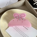 Close-up of pink acetic acid hair claw clip with sparkling rhinestones in bow design - 7cm / Pink