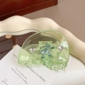 Close-up of a green acetate hair claw clip with heart rhinestones and dinosaur detail - Dinosaur / Green