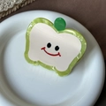 Close-up of cute green apple-shaped acetate hair claw clip with a smiling face on ceramic tray - Cyan Apple 6.8cm