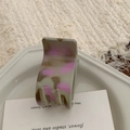 Close-up of a matte grey and pink spotted hair claw clip on an aesthetic tray - Ponytail Clip