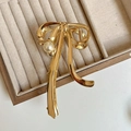 Dettaglio della molletta per capelli a fiocco dorato con perla su vassoio in velluto - Oro