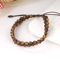 Dettaglio macro di perle in occhio di tigre a doppia fila su bracciale intrecciato regolabile - Occhio di Tigre