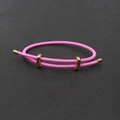 Détail macro du bracelet en fil d'acier tressé magenta avec boucles dorées réglables - Rose foncé
