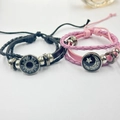 Detailed close-up of woven couple bracelets with sun and moon luminous glass gems - Black Sun + Pink Moon