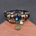 Dettaglio del bracciale multistrato in pelle intrecciata Toro con perline e ciondolo vintage - Toro Luminoso