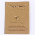 Detalle del collar con colgante de Capricornio en oro sobre tarjeta de regalo kraft marrón - Capricornio