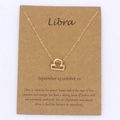 Detail of Libra zodiac symbol gold necklace on a character trait display card - Libra