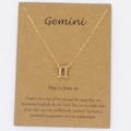 Detalle del collar dorado del signo Géminis sobre tarjeta de descripción personal - Géminis