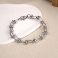Silver chain bracelet with knot links and lobster clasp on white ceramic tray - Square Knot Link Chain 1 (BST-0144)
