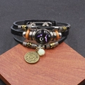 Vista macro del bracciale multistrato Gemelli in pelle con ciondolo in bronzo e vetro inciso - Gemelli Luminosi